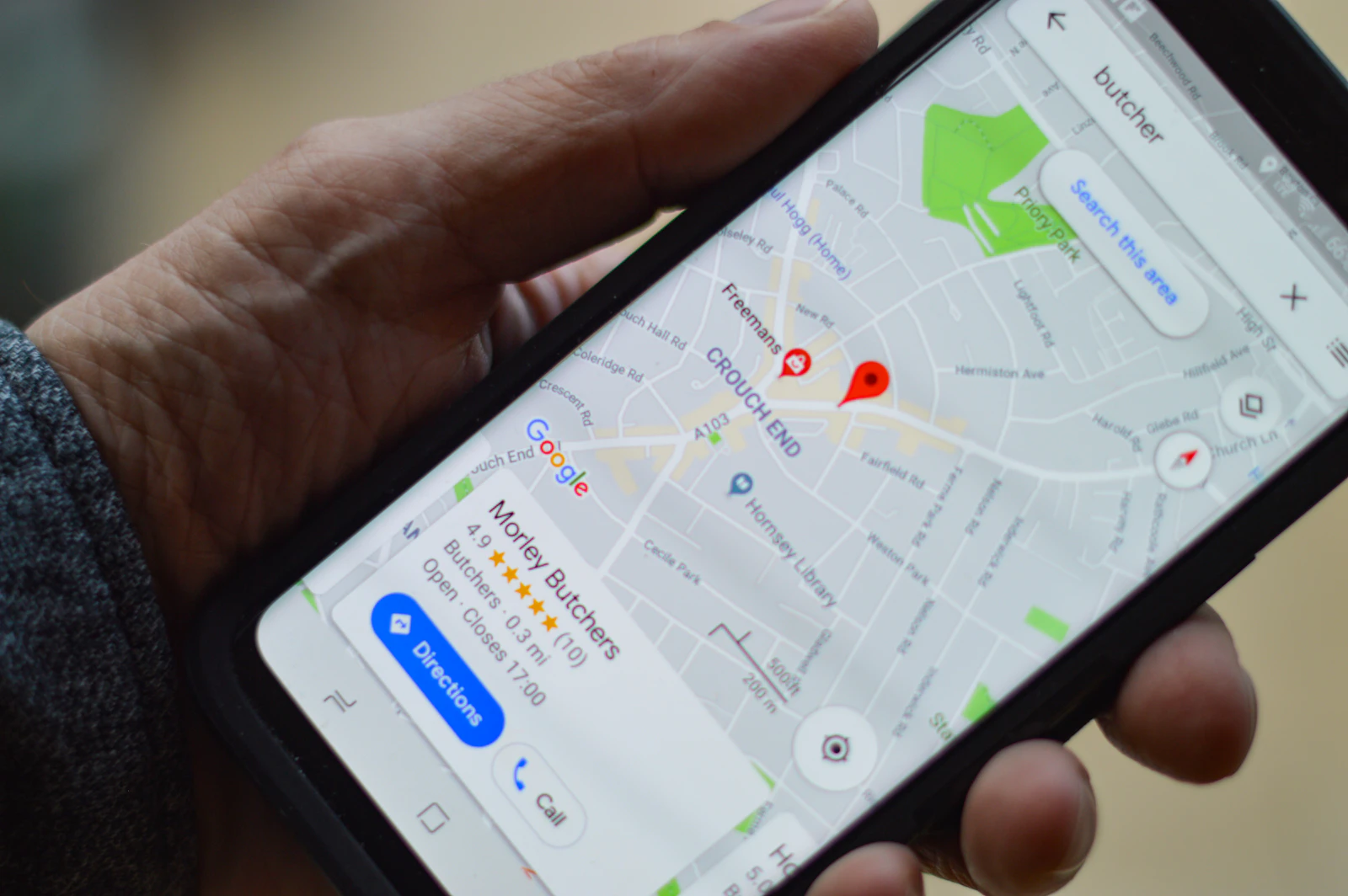 Ruka drži mobitel s otvorenim Google kartama i prikazom lokalne trgovine.