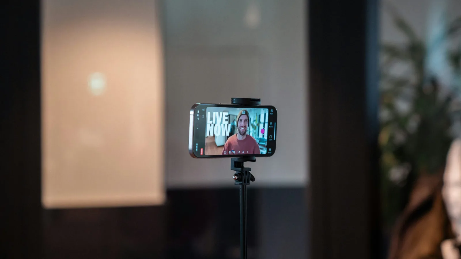 Pametni telefon na stativu snima osobu u studiju za izradu video sadržaja.