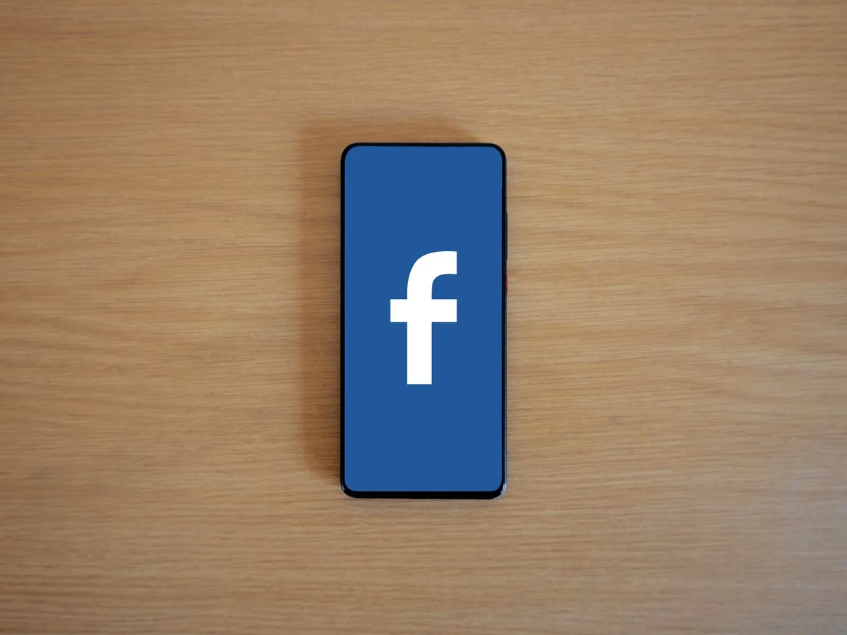 Telefon s Facebook logotipom na drvenom stolu